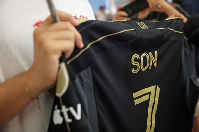 A supporter of South Korean football player Son Heung-min holds a LAFC jersey as he waits for his arrival at the Los Angeles International Airport in Los Angeles, California on August 5, 2025. ESPN and The Athletic report that Son, who left Tottenham Hotspur last weekend, will sign with LAFC for an MLS-record transfer fee of $26 million. LAFC announced a news conference for a "major announcement" on August 6 at 2 pm local time (2100 GMT) that would seem to be the unveiling of Son. Patrick T. Fallon / AFP