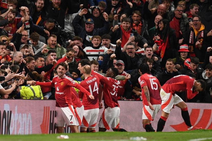 Manchester United's English defender #05 Harry Maguire (C) and teammates celebrate with their fans after Maguire scores their fifth goal during the UEFA Europa league quarter-final final, second leg football match between Manchester United and Lyon at Old Trafford stadium in Manchester, north west England, on April 17, 2025.  Oli SCARFF / AFP