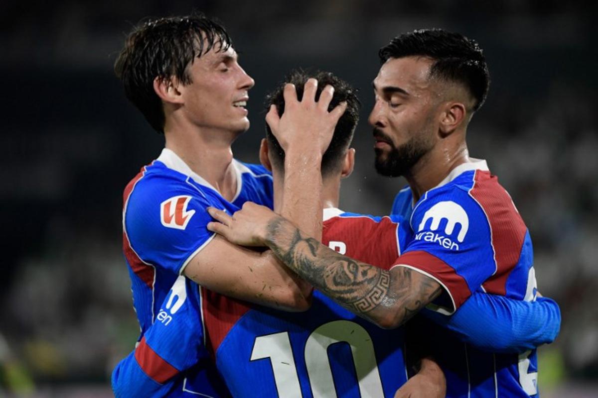 Atletico Madrid's Spanish forward #10 Alex Baena (C) celebrates with teammates after scoring their second goal during the Spanish league football match between Real Betis and Club Atletico de Madrid at the Cartuja Stadium in Seville on October 27, 2025.  CRISTINA QUICLER / AFP