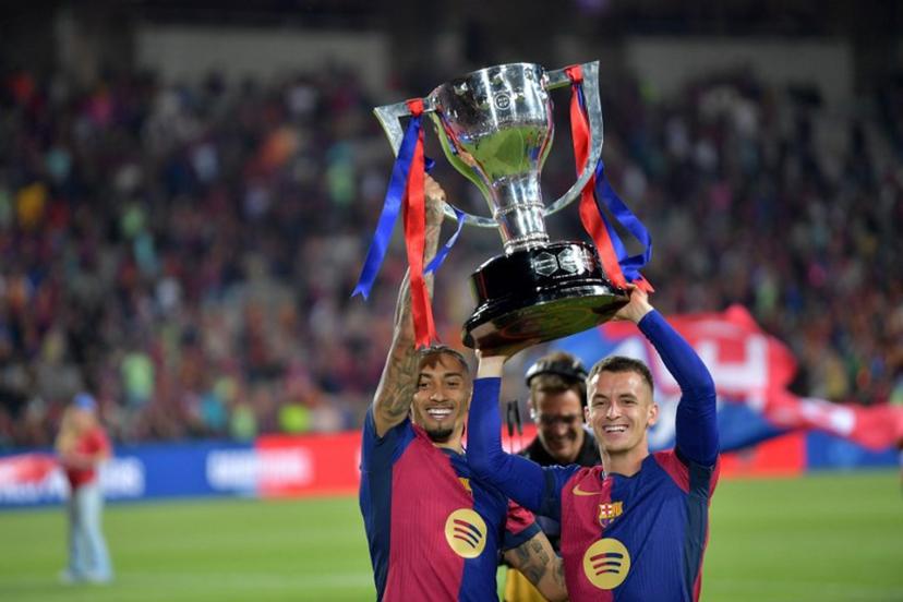 Barcelona's Brazilian forward #11 Raphinha (L) and Barcelona's Spanish midfielder #17 Marc Casado raise their trophy as they celebrate their 28th Liga title after the Spanish league football match between FC Barcelona and Villarreal CF at Estadi Olimpic Lluis Companys in Barcelona on May 18, 2025.  MANAURE QUINTERO / AFP