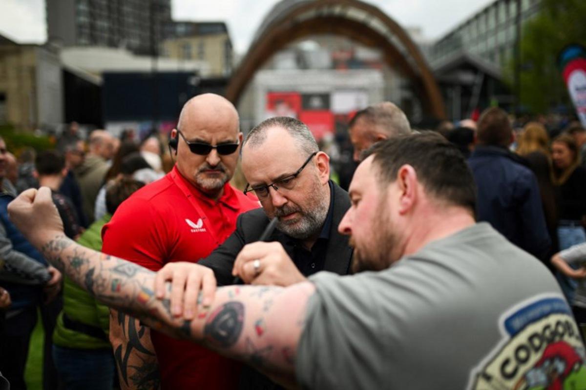 Welsh snooker player Mark Williams (C) signs the arm of a supporter as he arrives for the photo-call during the media day launching the start of the World Snooker Championship 2025 at Crucible Theatre on April 18, 2025 in Sheffield, northern England. The World Snooker Championship 2025 will take place from April 19 to May 5, 2025. Oli SCARFF / AFP