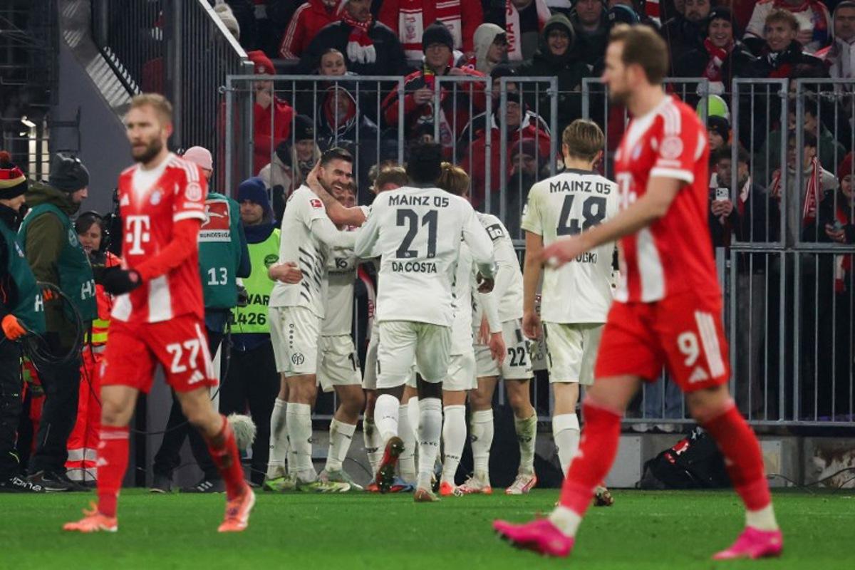 Mainz' South Korean midfielder #07 Lee Jae-Sung (hidden) celebrates scoring the 1-2 goal with his teammates during the German first division Bundesliga football match between FC Bayern Munich and Mainz 05 in Munich, southern Germany on December 14, 2025.  Karl-Josef HILDENBRAND / AFP