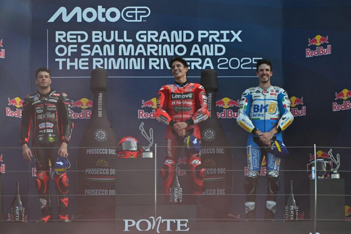 Ducati Lenovo Team's Spanish MotoGP rider Marc Marquez celebrates his victory on the podium next to Aprilia Racing team's Italian MotoGP rider Marco Bezzecchi (L) and BK8 Gresini Racing MotoGP team's Spanish MotoGP rider Alex Marquez (R) after the San Marino Moto GP Grand Prix at the Misano World Circuit Marco Simoncelli, in Misano Adriatico, northern Italy, on September 14, 2025.  Andreas SOLARO / AFP