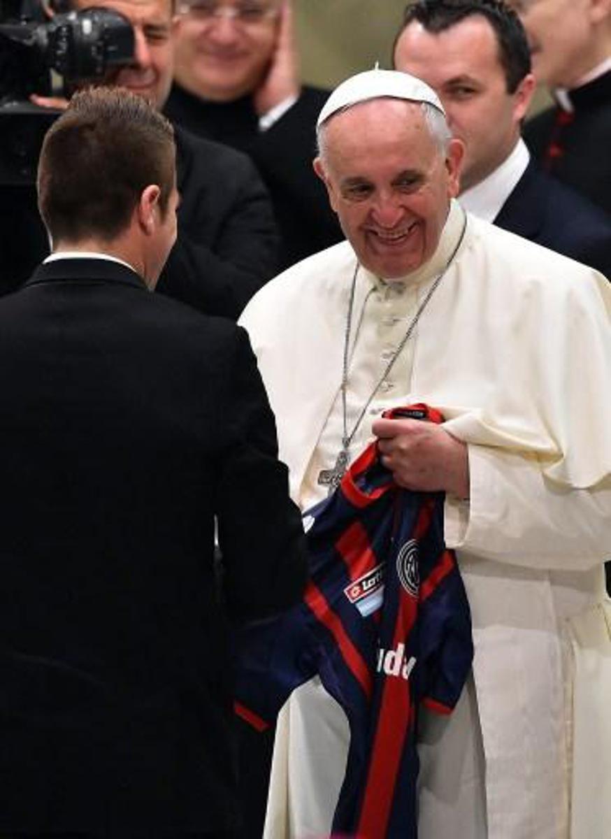 Pope Francis received a San Lorenzo's jersey as he welcomes players of the Argentinian football team San Lorenzo, before his general audience in the Paul VI hall at the Vatican on August 20, 2014. AFP PHOTO / GABRIEL BOUYS