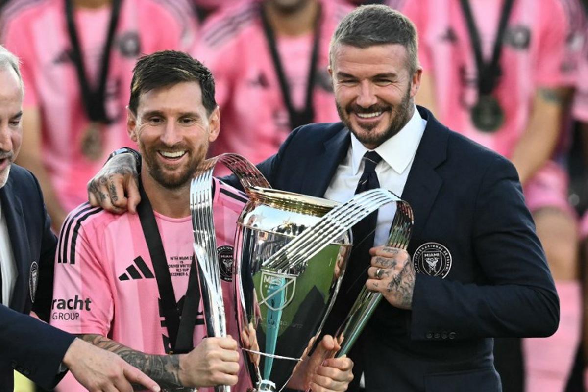 Inter Miami's Argentine forward #10 Lionel Messi (L) poses with the trophy next to the team's owner David Beckham (R) after winning the Major League Soccer (MLS) Cup final between Inter Miami and the Vancouver Whitecaps at Chase Stadium in Fort Lauderdale, Florida, on December 6, 2025.  CHANDAN KHANNA / AFP