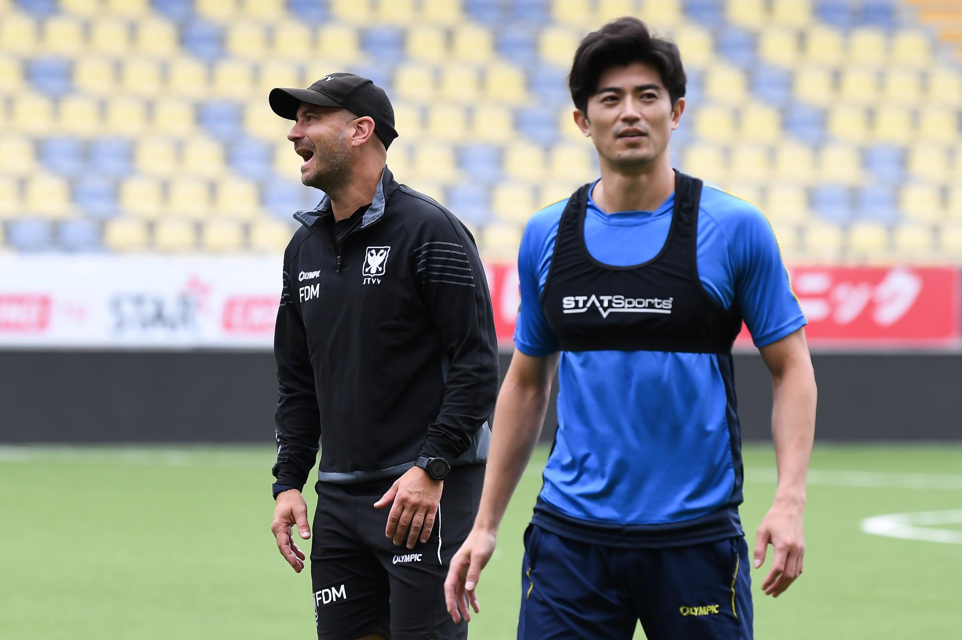 STVV's head coach Frederic De Meyer and STVV's Shogo Taniguchi pictured during a training session of Belgian soccer team Sint-Truidense V.V., Wednesday 19 August 2026 in Sint-Truiden, in preparations of the first leg of the play-off round for the UEFA Europa League league phase, against Cypriot team AC Omonoia Nicosia. BELGA PHOTO JILL DELSAUX