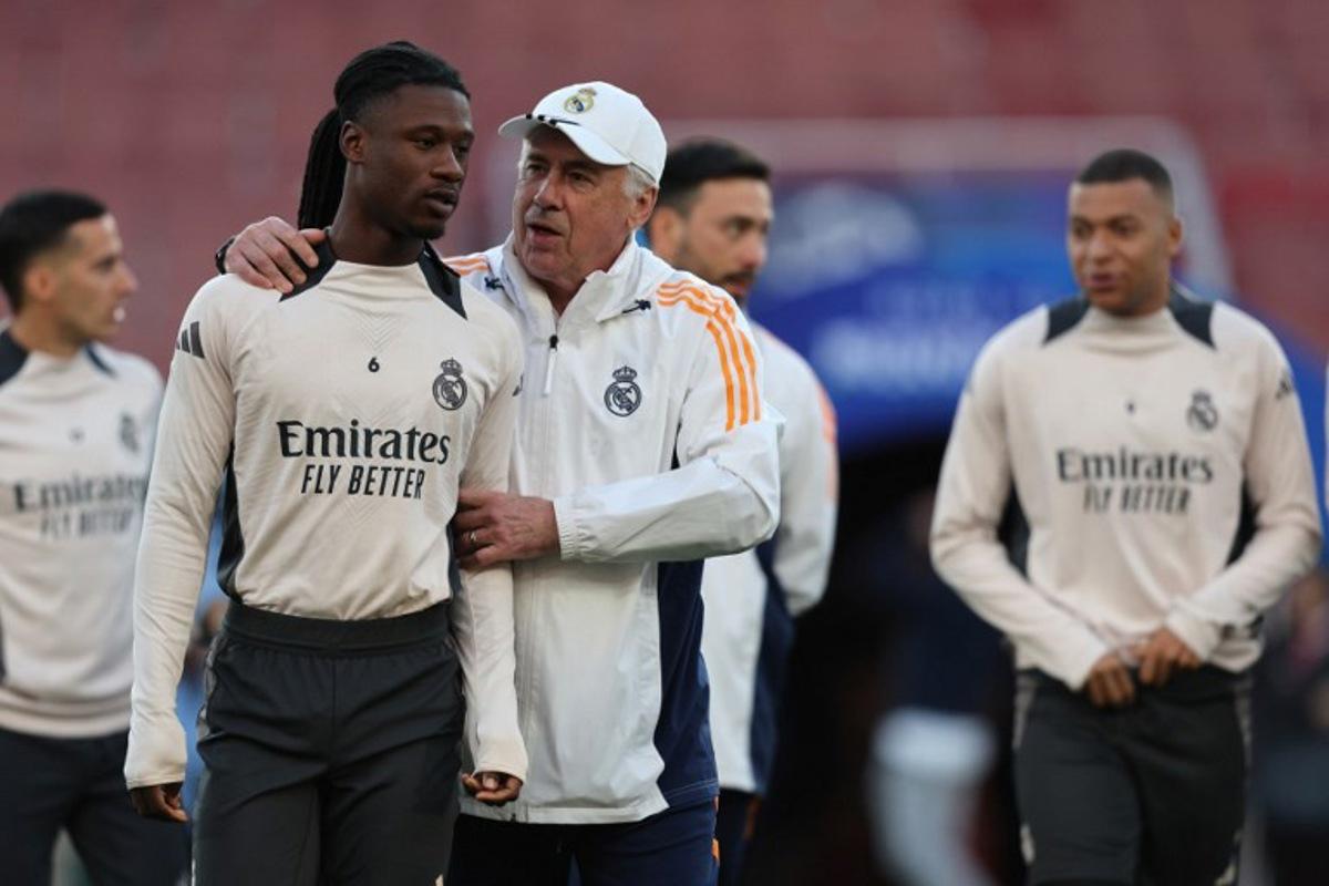 Real Madrid's Italian coach Carlo Ancelotti (C) speaks with Real Madrid's French midfielder #06 Eduardo Camavinga (L) during a training session at the Emirates stadium in London on April 7, 2025, on the eve of their UEFA Champions League Quarter final first leg football match against Arsenal.  Adrian Dennis / AFP