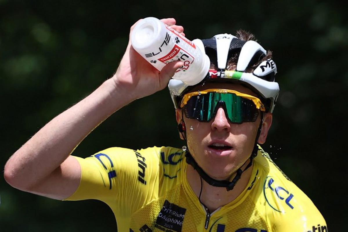 UAE Team Emirates XRG's Slovenian rider Tadej Pogačar wearing the overall leader's yellow jersey pours water on himself during the 7th stage of the 77th edition of the Criterium du Dauphine cycling race, 131,6 km between Grand-Aigueblanche and Valmeinier, on June 14, 2025.  Anne-Christine POUJOULAT / AFP