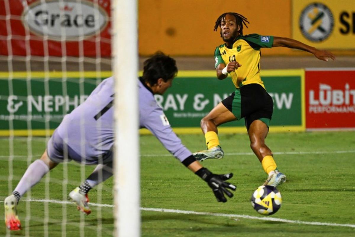 Jamaica's forward #19 Rumarn Burrell (R) eyes the ball after a shot against Guatemala's goalkeeper #01 Nicholas Hagen during the 2026 FIFA World Cup Concacaf qualifier football match between Jamaica and Guatemala at the Independence Park stadium in Kingston on June 10, 2025.  Ricardo Makyn / AFP