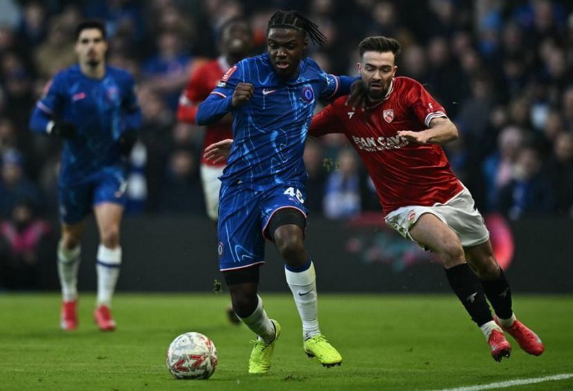 Morecambe's Welsh midfielder #07 Gwion Edwards (R) fouls Chelsea's Belgian midfielder #45 Romeo Lavia during the English FA Cup third round football match between Chelsea and Morecambe at Stamford Bridge in London on January 11, 2025.  Ben STANSALL / AFP