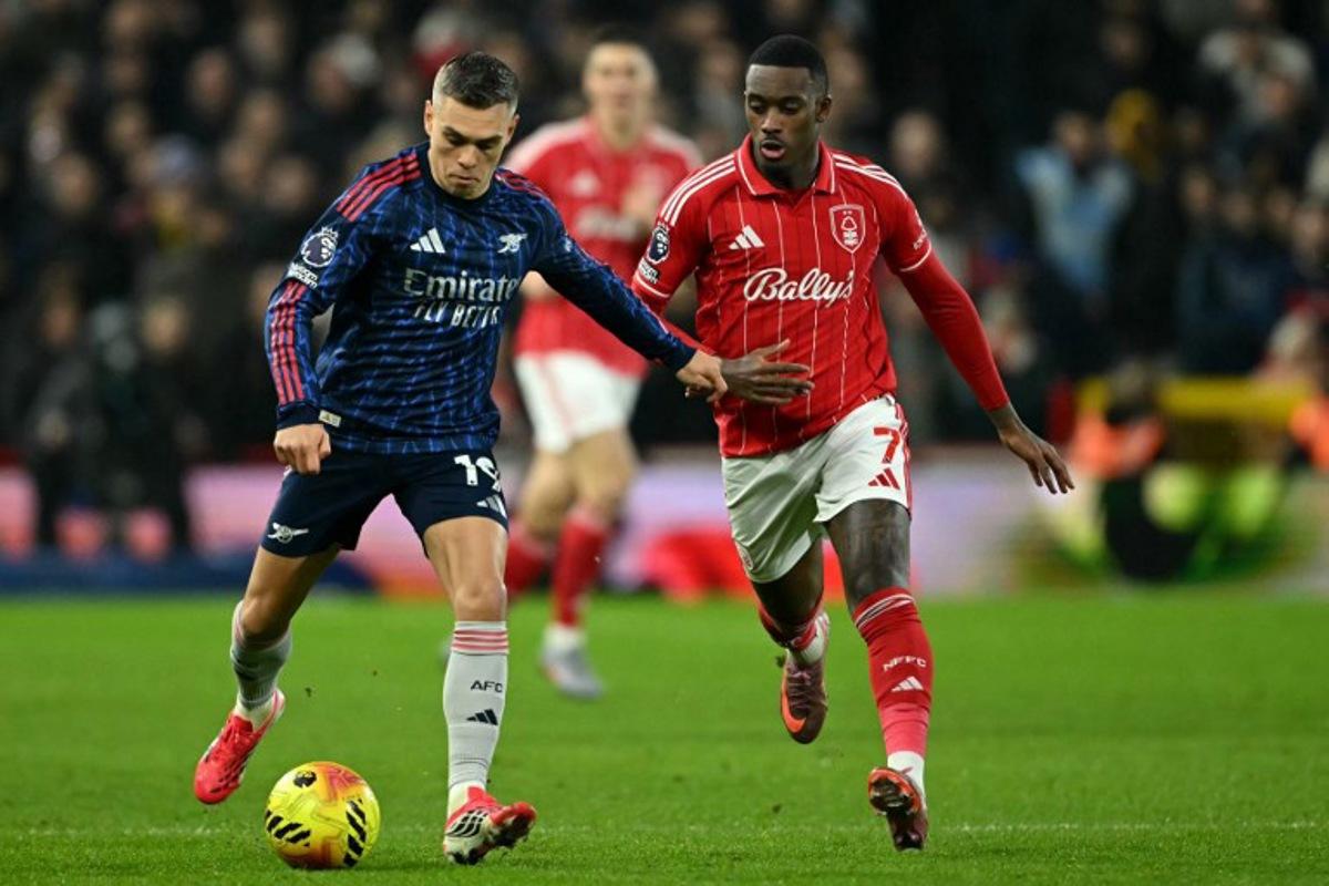 Arsenal's Belgian midfielder #19 Leandro Trossard runs with the ball whilst under pressure from Nottingham Forest's English midfielder #07 Callum Hudson-Odoi during the English Premier League football match between Nottingham Forest and Arsenal at The City Ground in Nottingham, central England, on January 17, 2026.  JUSTIN TALLIS / AFP