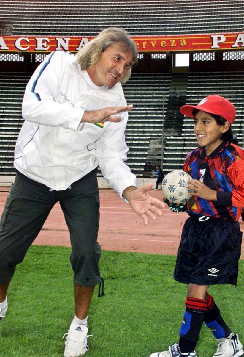 (FILES) Argentinian goalkeeper Hugo Orlando Gatti (L) jokes with a child on January 22, 2004 at the Hernando Siles stadium in La Paz, Bolivia.    The so-called 'El Loco' Gatti, emblematic goalkeeper of Argentine football and former member of the national team, died on April 20, 2025 at the age of 80, according to CONMEBOL sources. Gatti had been in hospital in Buenos Aires for two months with a hip fracture, but his health had deteriorated due to pneumonia. Aizar RALDES / AFP