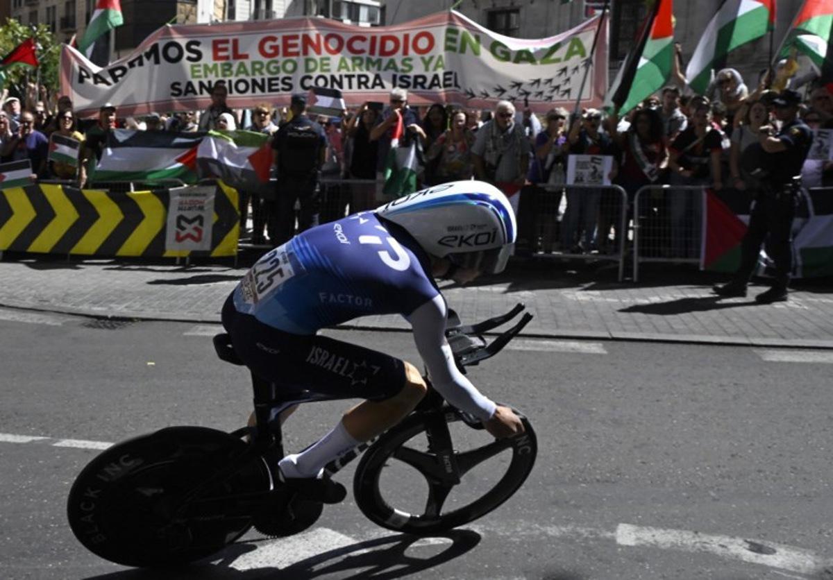 Pro-Palestinians protesters wave Palestinian flags as Team Israel Premier Tech's Israeli rider Nadav Raisberg competes during the 18th stage of the Vuelta a Espana, a 26 km race against the clock between Valladolid and Valladolid, on September 11, 2025.    Miguel RIOPA / AFP