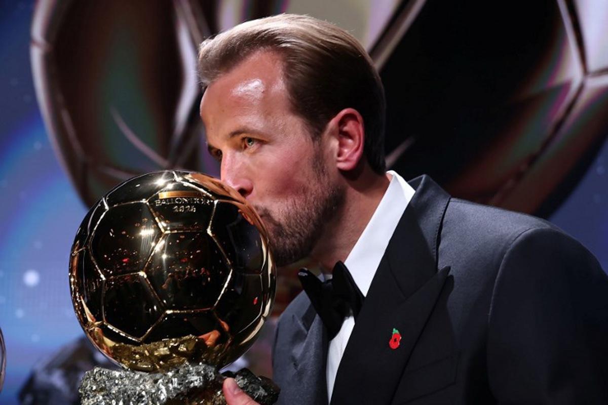 England and Bayern Munich forward Harry Kane kisses the trophy on stage after receiving the Ballon d'Or award for the best male footballer during the 2026 Ballon d'Or France Football award ceremony at the Palladium Theatre in London on October 26, 2026.  FRANCK FIFE / AFP