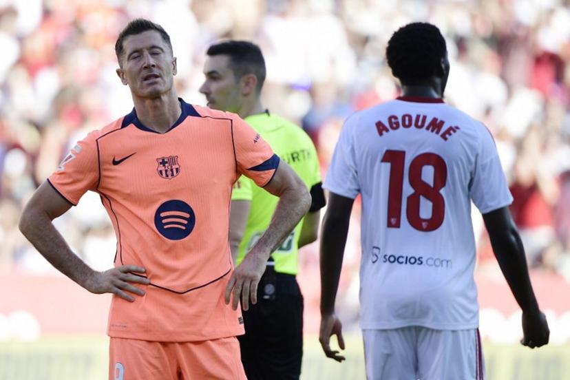 Barcelona's Polish forward #09 Robert Lewandowski (L) reacts to missing a penalty kick during the Spanish league football match between Sevilla FC and FC Barcelona at Ramon Sanchez Pizjuan Stadium in Seville on October 5, 2025.  CRISTINA QUICLER / AFP