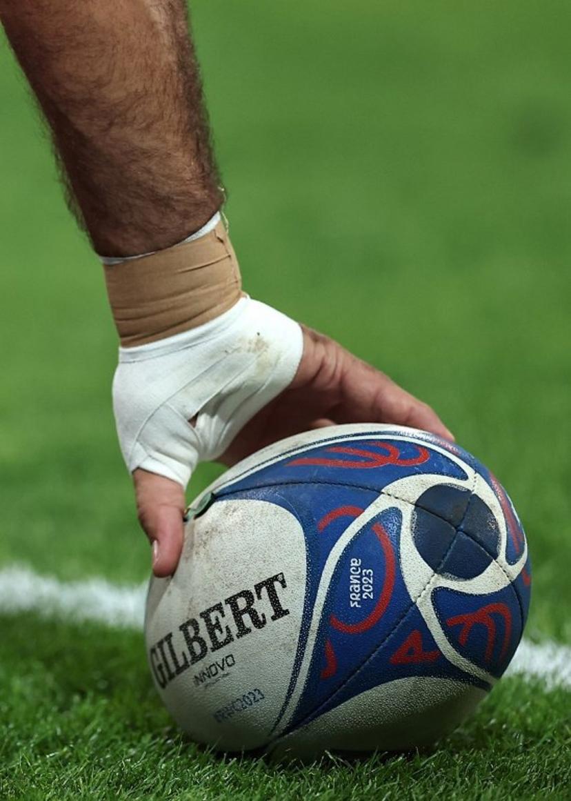 A players picks up a rugby ball ahead of the France 2023 Rugby World Cup Pool B match between Scotland and Romania at Pierre-Mauroy stadium in Villeneuve-d'Ascq near Lille, northern France, on September 30, 2023.  FRANCK FIFE / AFP