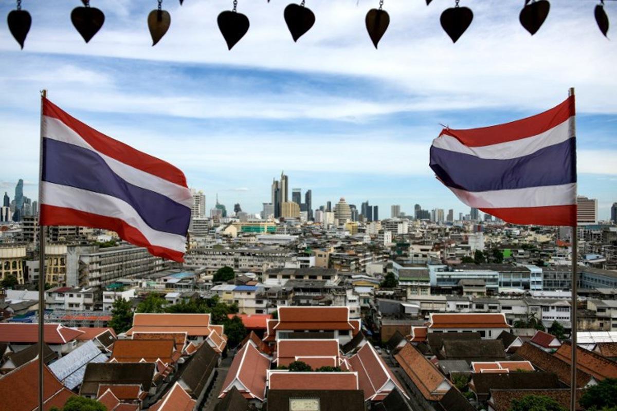 This photo taken on June 26, 2023 shows Thai flags fluttering in the wind in the backdrop of Bangkok skyline seen from the Wat Saket Buddhist temple.  Amaury PAUL / AFP