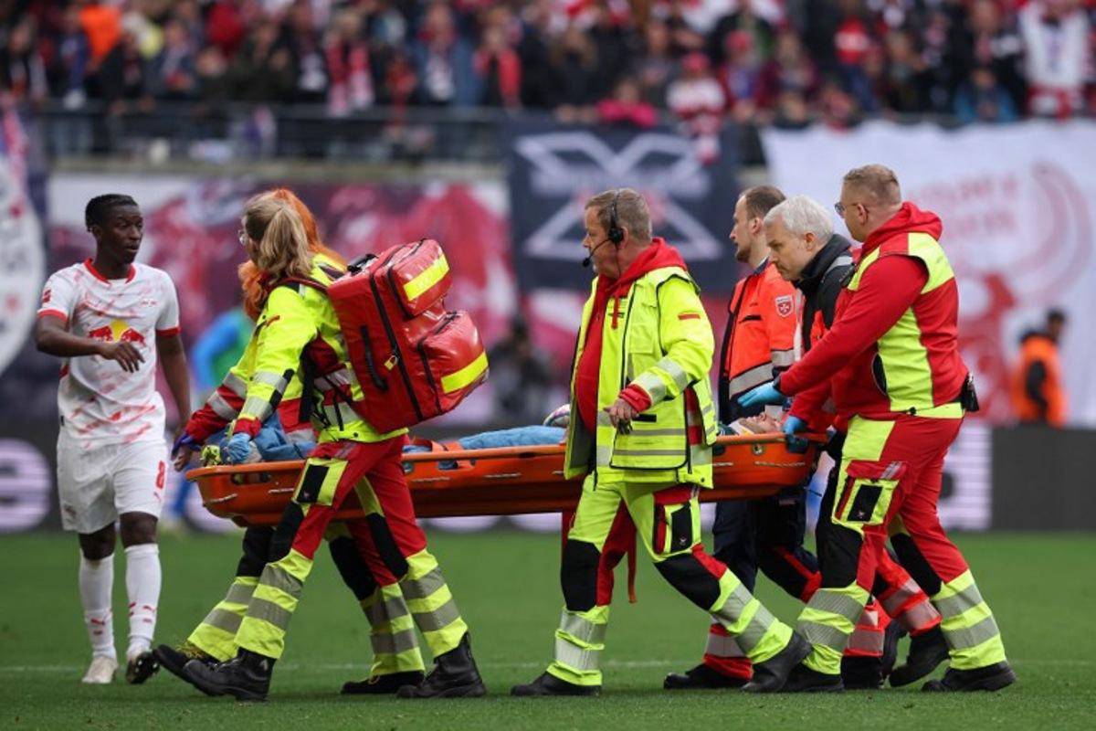 Leipzig's Malian midfielder #08 Amadou Haidara (L) checks on Leipzig's Hungarian goalkeeper #01 Peter Gulacsi who is stretchered off after sustaining an injury during the German first division Bundesliga football match between RB Leipzig and Holstein Kiel in Leipzig, eastern Germany on April 19, 2025.  RONNY HARTMANN / AFP