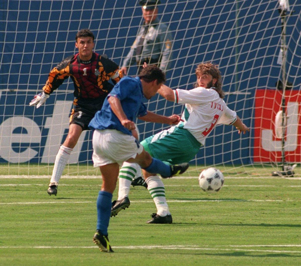 Italian forward Roberto Baggio kicks the ball past Bulgarian defender Trifon Ivanov and goalkeeper Borislav Mihaylov to score his first goal during the World Cup semifinal soccer match between Italy and Bulgaria 13 July 1994 in East Rutherford. Baggio scored another goal to help his team qualify for the final with a 2-1 victory.   AFP PHOTO/BOB STRONG  BOB STRONG / AFP