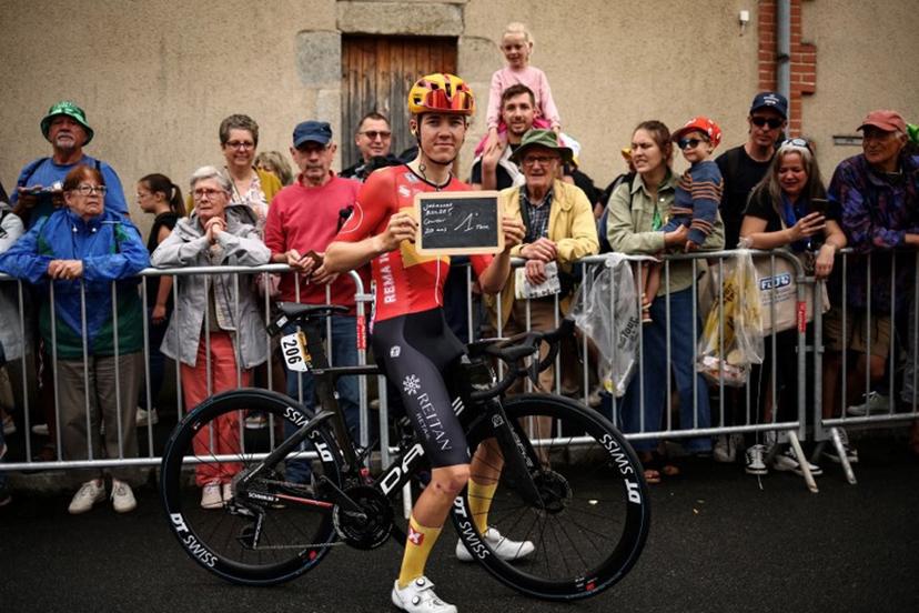 This photograph taken on July 10, 2024, shows Uno-X Mobility team's Norwegian rider Johannes Kulset posing with the chalkboad indicating his first Tour de France attendance at the start of the 11th stage of the 111th edition of the Tour de France cycling race, 211 km between Évaux-les-Bains and Le Lioran.  Anne-Christine POUJOULAT / AFP
