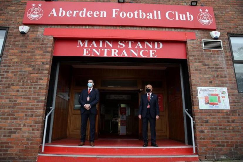 Security guards wearing face masks or covering due to the COVID-19 pandemic, stand at the entrance to Pittodrie Stadium in Aberdeen, northeast Scotland, on August 1, 2020, ahead of the Scottish Premier League football match between Aberdeen and Rangers.  Andrew Milligan / AFP / POOL