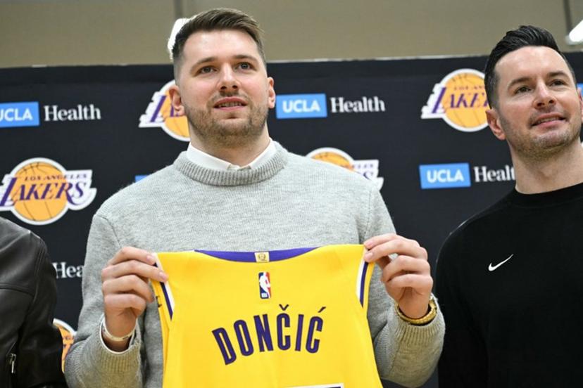 Slovenian basketball player Luka Doncic (L) holds up a jersey as he stands alongside Los Angeles Lakers head coach JJ Redick during a press conference introducing Doncic as the newest member of the Los Angeles Lakers, at the UCLA Health Training Center, in El Segundo, California on February 4, 2025. Slovenian star Luka Doncic said February 2, 2025 he thought he'd spend his entire NBA career in Dallas, thanking fans in Texas for making it feel like home a day after the Mavericks abruptly traded him to the Los Angeles Lakers. Patrick T. Fallon / AFP