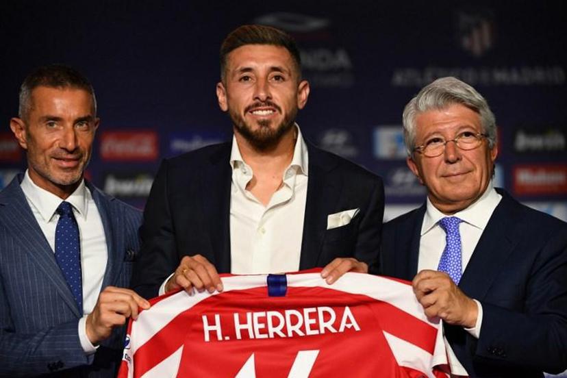 Atletico Madrid's new Mexican midfielder Hector Herrera holds his new jersey next to the Spanish football club's president Enrique Cerezo (R) and sports director Andrea Berta (L) during his official presentation at the Wanda Metropolitan stadium in Madrid on July 5, 2019.  GABRIEL BOUYS / AFP