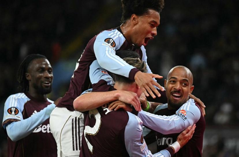 Aston Villa's Scottish midfielder #07 John McGinn is mobbed by teammates after scoring the opening goal during the UEFA Europa League, league stage football match between Aston Villa and Bologna at Villa Park in Birmingham, central England on September 25, 2025.  JUSTIN TALLIS / AFP