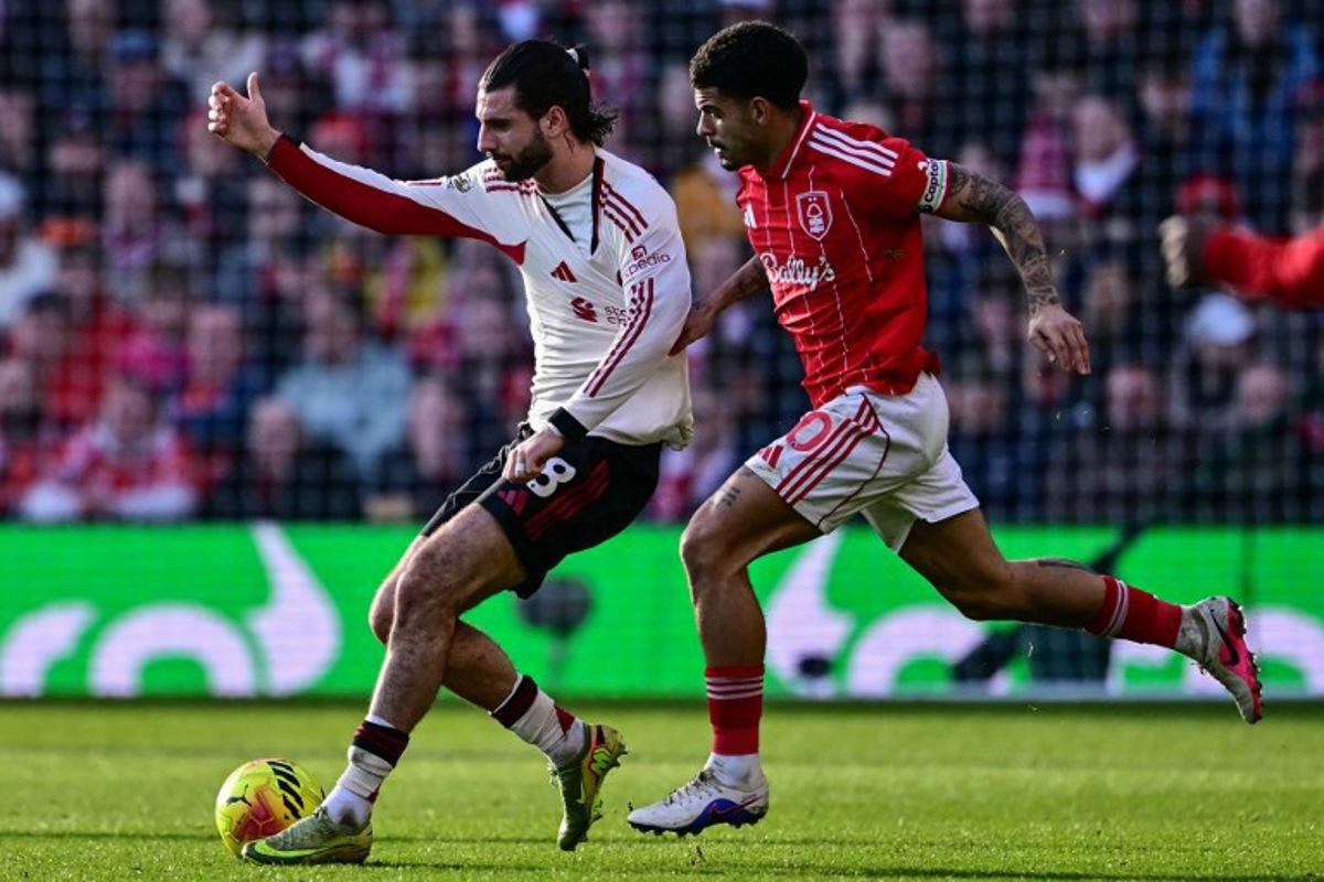 Nottingham Forest's English midfielder #10 Morgan Gibbs-White (R) pulls on the jersey of Liverpool's Hungarian midfielder #08 Dominik Szoboszlai (L) during the English Premier League football match between Nottingham Forest and Liverpool at The City Ground in Nottingham, central England on February 22, 2026.  Ben STANSALL / AFP