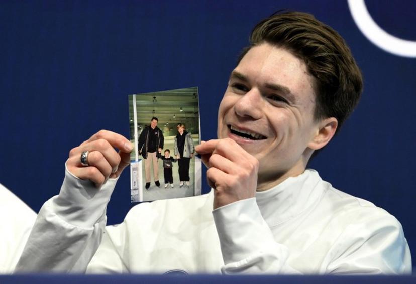 USA's Maxim Naumov holds a picture of his parents, who died in a plane crash last year, after competing in the figure skating men's singles short program during the Milano Cortina 2026 Winter Olympic Games at Milano Ice Skating Arena in Milan on February 10, 2026. Naumov's parents Vadim Naumov and Evgenia Shishkova died after a mid-air collision of an American Airlines plane and an US Army helicopter in Washington DC on January 29, 2025. WANG Zhao / AFP