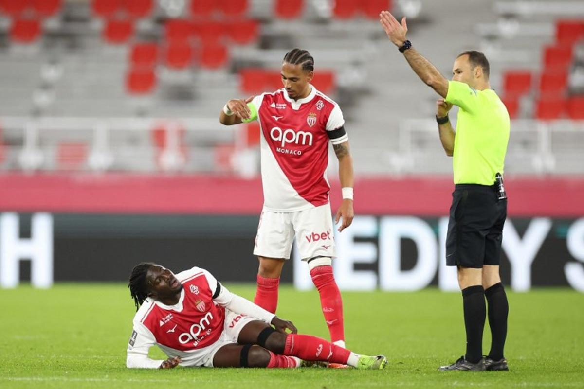 Monaco's Ghanaian defender #22 Mohammed Salisu (L) sustains an injury during the French L1 football match between AS Monaco and Olympique Lyonnais (OL) at the Stade Louis II in the Principality of Monaco on January 3, 2026.  Valery HACHE / AFP