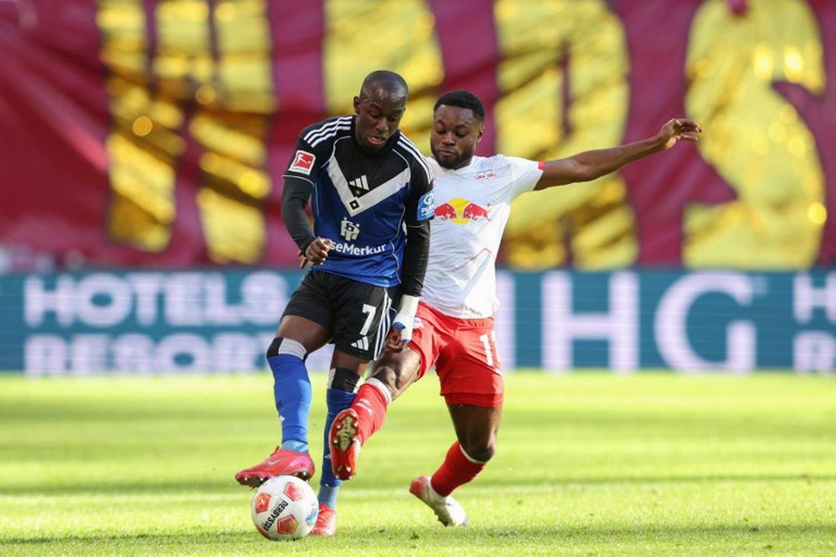 Hamburg's French-Ivorian forward #07 Jean-Luc Dompe  (L) and Leipzig's German midfielder #17 Ridle Baku vie for the ball during the German first division Bundesliga football match RB Leipzig v Hamburg SV in Leipzig, eastern Germany on October 18, 2025.  Ronny HARTMANN / AFP