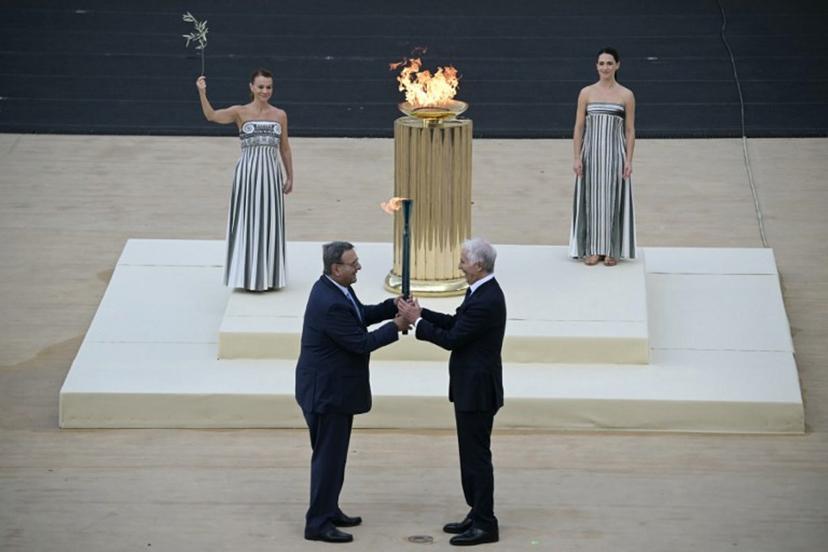 Hellenic Olympic Committee President Isidoros Kouvelos (L) and President of the Italian National Olympic Committee and CEO of the Milan Cortina 2026 Winter Olympic Giovanni Malago (R) hand the torch next to Greek actress Mary  Mina playing the role of the High Priestess, during the handover Olympic flame ceremony for the Milano-Cortina 2026 Winter Olympic Games and Paralympic Games, at the Panathinean stadium in Athens, on December 4, 2025.  Angelos Tzortzinis / AFP