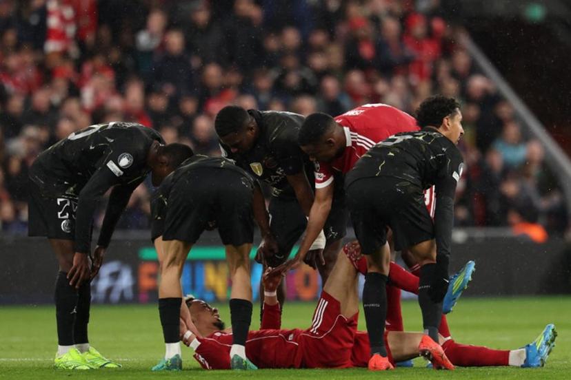 Players care for Liverpool's French striker #22 Hugo Ekitike who lies injured during the UEFA Champions League quarter final, second-leg football match between Liverpool and Paris Saint-Germain at Anfield in Liverpool, north west England on April 14, 2026.  FRANCK FIFE / AFP