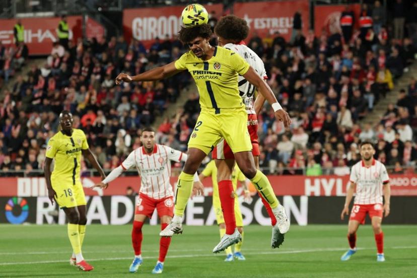 Villarreal's Portuguese defender #12 Renato Veiga wins a header against Girona's Belgian defender #20 Axel Witsel during the Spanish league football match between Girona FC and Villarreal CF at Montilivi Stadium in Girona on April 6, 2026.  Lluis GENE / AFP