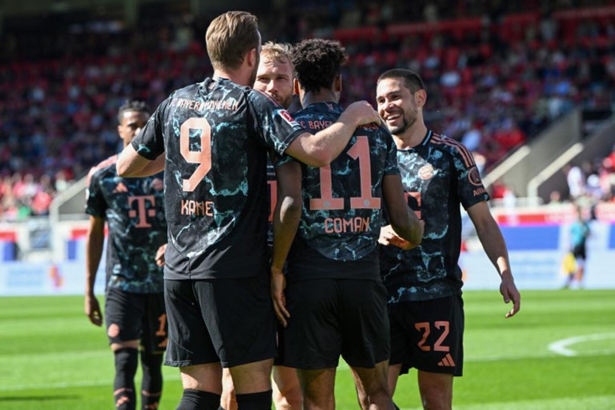 Bayern Munich's French forward #11 Kingsley Coman celebrates scoring the 0-3 goal with his teammates including Bayern Munich's English forward #09 Harry Kane (L) during the German first division Bundesliga football match between Heidenheim and Bayern Munich in Heidenheim, southern Germany on April 19, 2025.  THOMAS KIENZLE / AFP