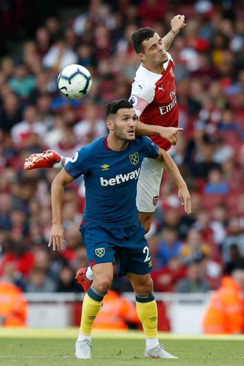 Arsenal's Swiss midfielder Granit Xhaka (R) jumps over West Ham United's Spanish striker Lucas Perez (L) during the English Premier League football match between Arsenal and West Ham United at the Emirates Stadium in London on August 25, 2018.   Ian KINGTON / AFP RESTRICTED TO EDITORIAL USE. No use with unauthorized audio, video, data, fixture lists, club/league logos or 'live' services. Online in-match use limited to 120 images. An additional 40 images may be used in extra time. No video emulation. Social media in-match use limited to 120 images. An additional 40 images may be used in extra time. No use in betting publications, games or single club/league/player publications.

