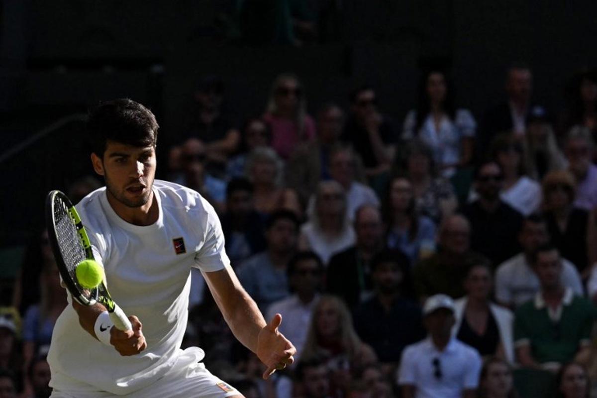 Spain's Carlos Alcaraz plays a forehand return to Britain's Cameron Norrie during their men's singles quarter-final tennis match on the ninth day of the 2025 Wimbledon Championships at The All England Lawn Tennis and Croquet Club in Wimbledon, southwest London, on July 8, 2025.  Glyn KIRK / AFP