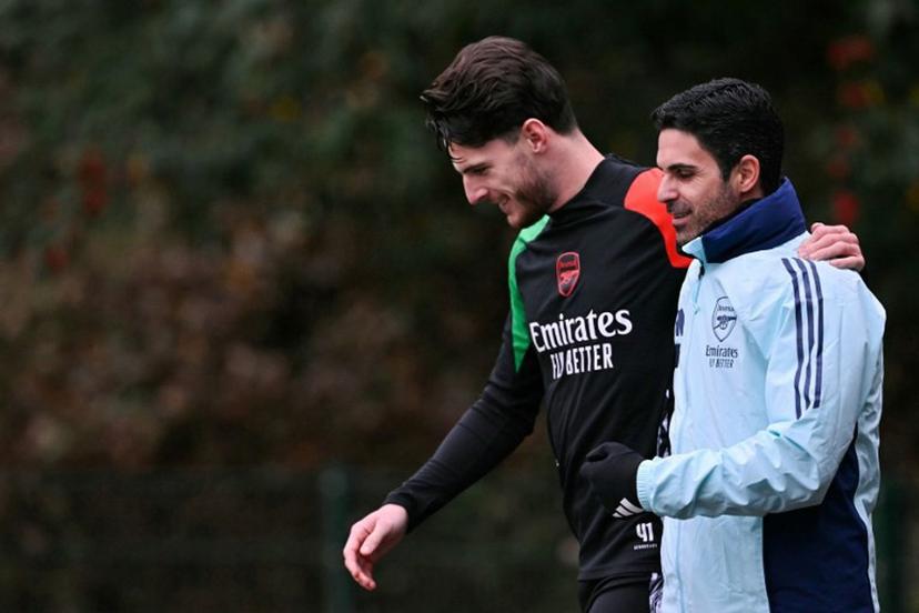Arsenal's English midfielder #41 Declan Rice (L) and Arsenal's Spanish manager Mikel Arteta (R) speak together as they arrive to take part in a training session at the Arsenal Training centre in Shenley, north of London on December 10, 2024 on the eve of their UEFA Champions League football match against Monaco.  Glyn KIRK / AFP