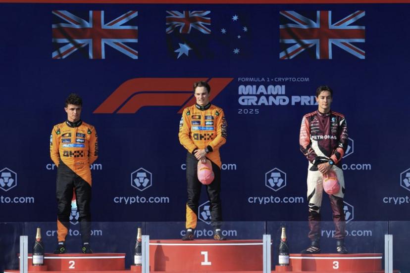 Winner McLaren's Australian driver Oscar Piastri (C) stands on the podium alongside McLaren's British driver Lando Norris, second place, and Mercedes' British driver George Russell, third place,  after the 2025 Miami Formula One Grand Prix at Miami International Autodrome in Miami Gardens, Florida, on May 4, 2025.   CHARLY TRIBALLEAU / AFP