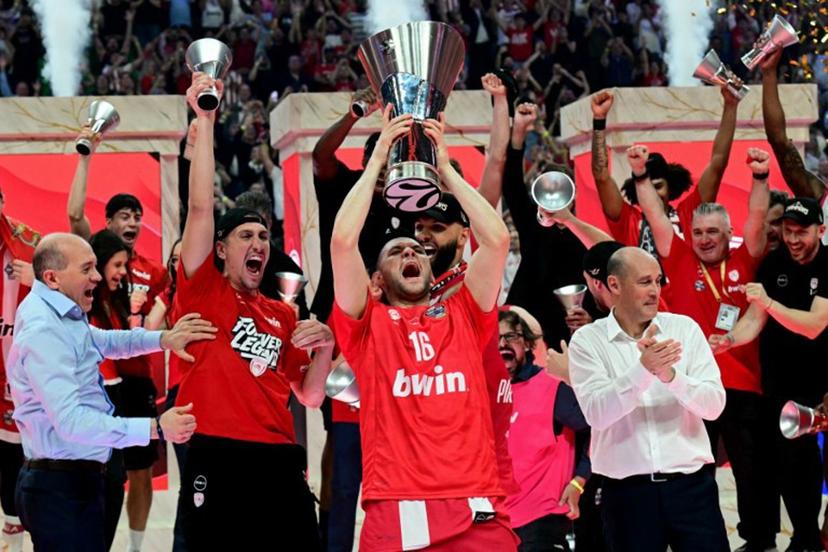 Olympiacos' Greek forward #16 Kostas Papanikolaou (C) raises the winners trophy as he celebrates with team mates and staff after winning the men's EuroLeague final basketball match between Olympiacos Piraeus and Real Madrid at the Telekom Center Athens in Athens on May 24, 2026.   Angelos Tzortzinis / AFP