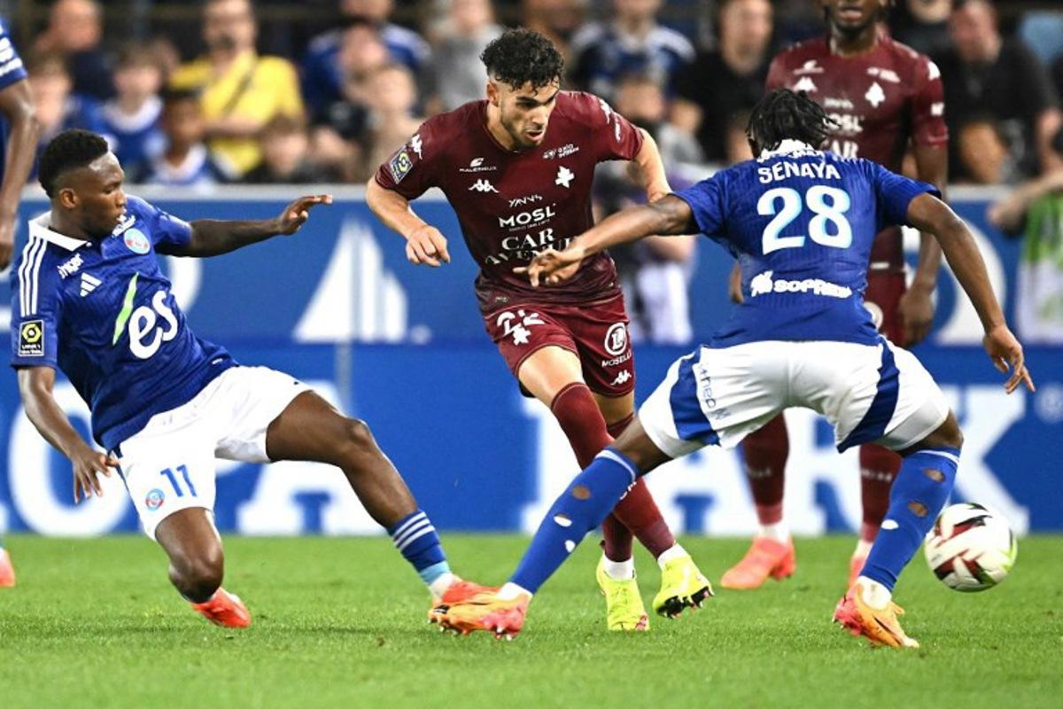 Metz's Algerian French defender #22 Kevin Van den Kerkhof (C) fights for the ball with Strasbourg's Ivorian Malian forward #11 Moise Sahi Dion (L) and Strasbourg's French defender #28 Marvin Senaya during the French L1 football match between RC Strasbourg Alsace and FC Metz at the Stade de la Meinau in Strasbourg, eastern France, on May 12, 2024.   SEBASTIEN BOZON / AFP