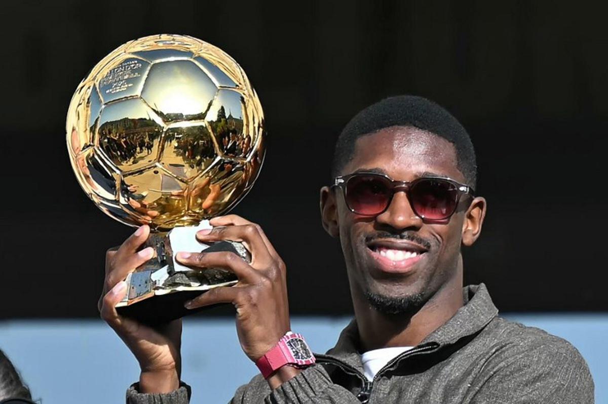 Paris Saint-Germain's French forward Ousmane Dembele holds the 2025 Ballon d'Or trophy during a presentation ceremony at the City Hall in Evreux, his hometown and where he started playing club football, on October 12, 2025.  LOU BENOIST / AFP
