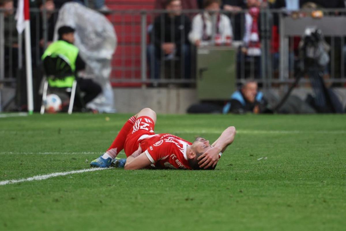 Bayern Munich's Portuguese defender #22 Raphael Guerreiro reacts in pain on the ground during the German first division Bundesliga football match between FC Bayern Munich and VfB Stuttgart in Munich, southern Germany, on April 19, 2026.  Karl-Josef HILDENBRAND / AFP