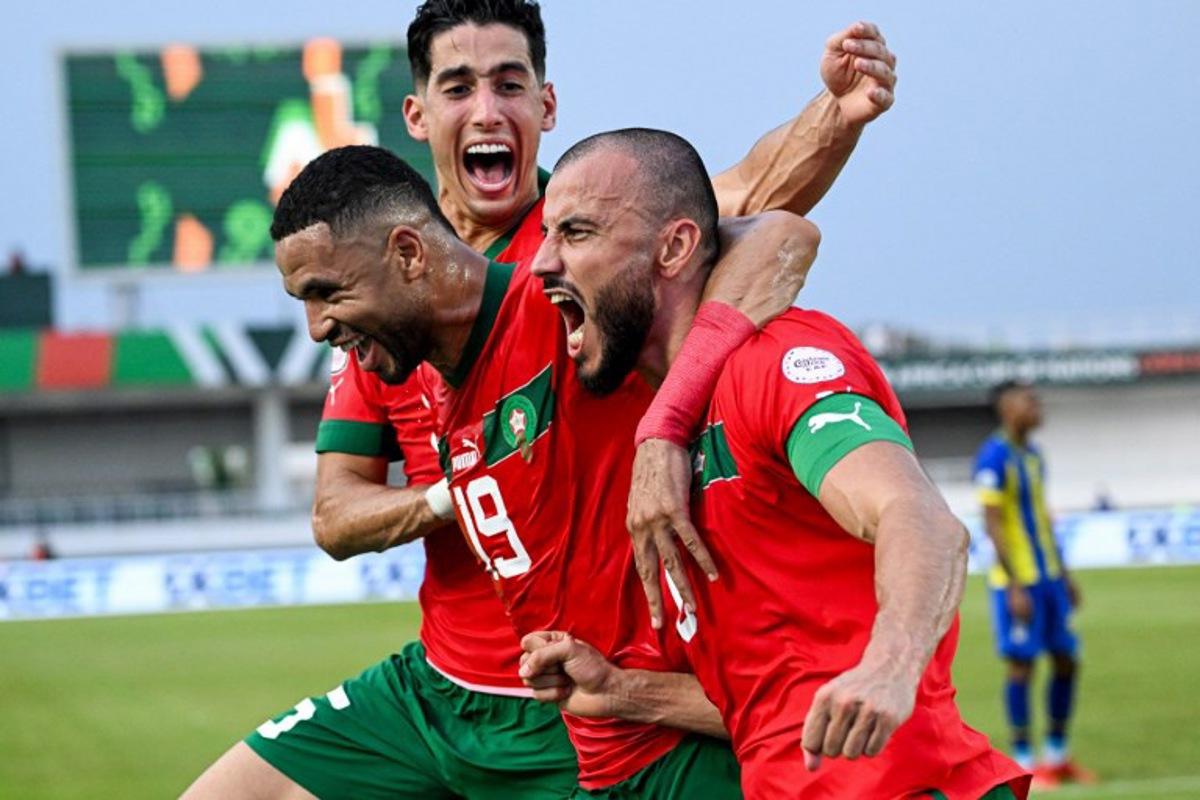 Morocco's defender #6 Romain Saiss (R) celebrates with Morocco's forward #19 Youssef En-Nesyri (C) and Morocco's defender #5 Nayef Aguerd (L) after scoring his team's first goal during the Africa Cup of Nations (CAN) 2024 group F football match between Morocco and Tanzania at Stade Laurent Pokou in San Pedro on January 17, 2024.  SIA KAMBOU / AFP
