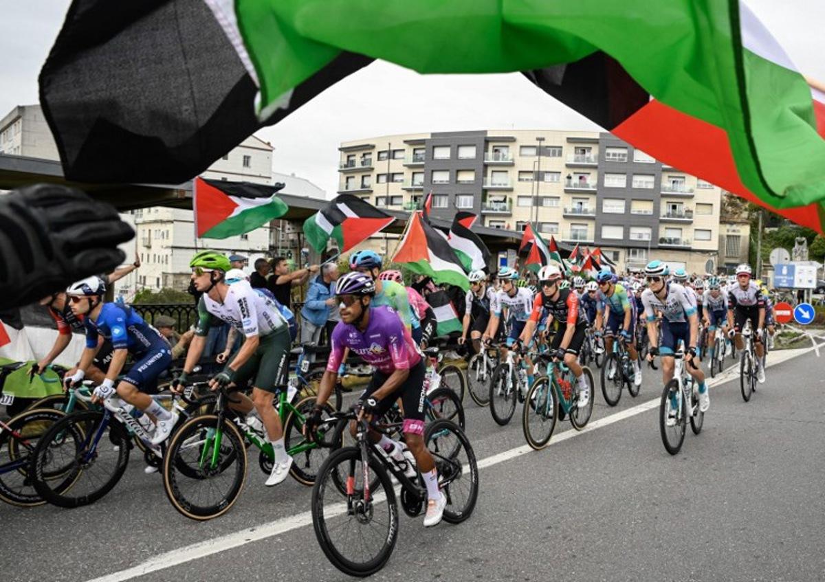 Pro-Palestinian protesters wave flags and shout as the peloton rides by in Poio at the start of the 16th stage of the Vuelta a Espana, a 172 km race between Poio and Castro de Herville, on September 9, 2025.    Miguel RIOPA / AFP