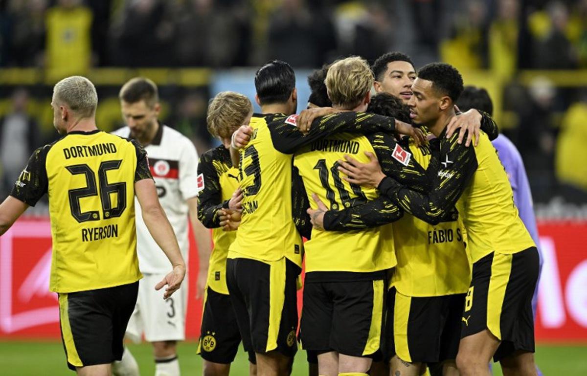 Dortmund's German forward #27 Karim Adeyemi (hidden) is congratulated by teammates after he scored the 2-0 goal during the German first division Bundesliga football match between BVB Borussia Dortmund and FC St Pauli in Dortmund, western Germany, on January 17, 2026.  INA FASSBENDER / AFP