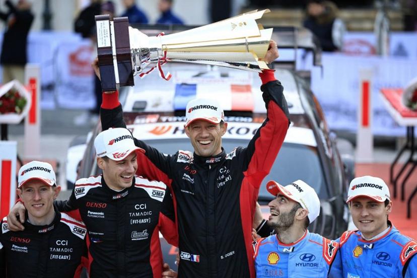 Second-placed Welsh driver Elfyn Evans (L), stands along side the winners French driver Sebastien Ogier as he holds up the trophy and his French co-driver Vincent Landais, and third-placed French driver Adrien Fourmaux (R) and French co-pilot Alexandre Coria (2nd R), as they celebrate on the podium after the 93rd WRC Monte-Carlo Rally, at the Place du Casino, in Monaco on January 26, 2025.  Valery HACHE / AFP