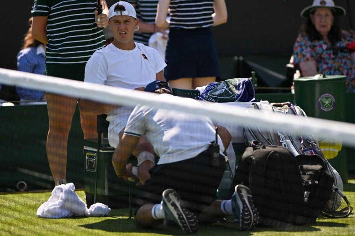 Denmark's Holger Rune receives medical treatment as he plays against Chile's Nicolas Jarry during their men's singles first round tennis match on the first day of the 2025 Wimbledon Championships at The All England Lawn Tennis and Croquet Club in Wimbledon, southwest London, on June 30, 2025.  Glyn KIRK / AFP