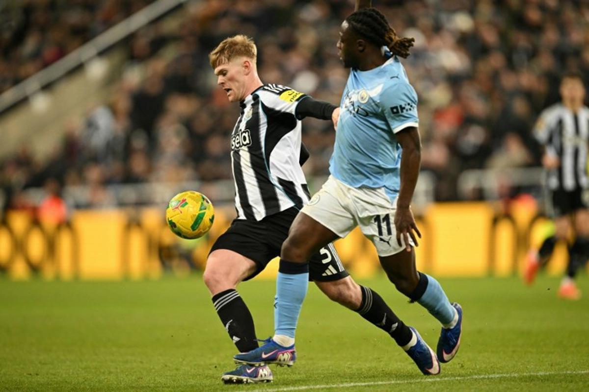 Newcastle United's English midfielder #20 Lewis Hall (L) vies with Manchester City's Belgian midfielder #11 Jeremy Doku (R) during the English League Cup semi-final first leg football match between Newcastle United and Manchester City at St James' Park in Newcastle-upon-Tyne, north east England on January 13, 2026.  Oli SCARFF / AFP